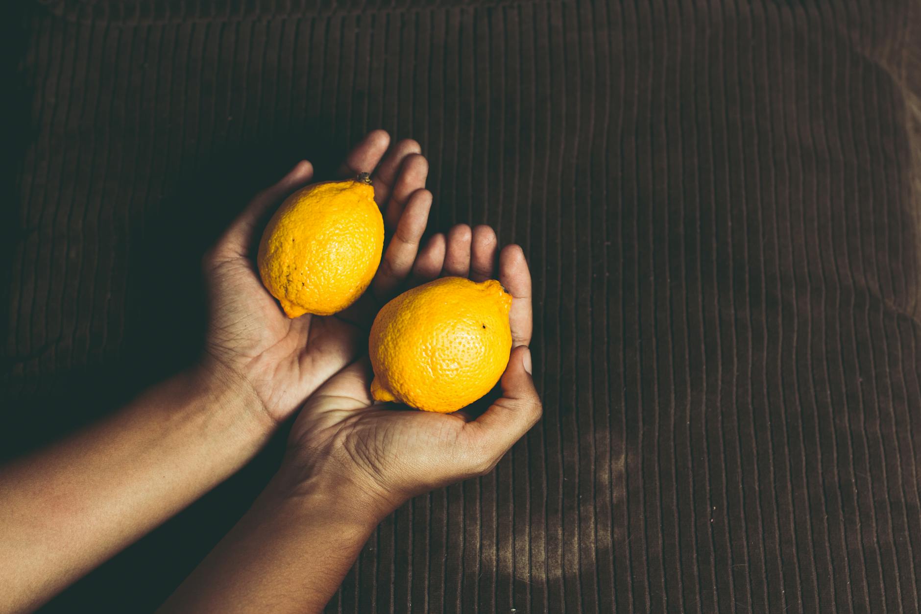 Close-up of two fresh lemons held in cupped hands, symbolizing the gentle, supportive approach lemon vibrators offer