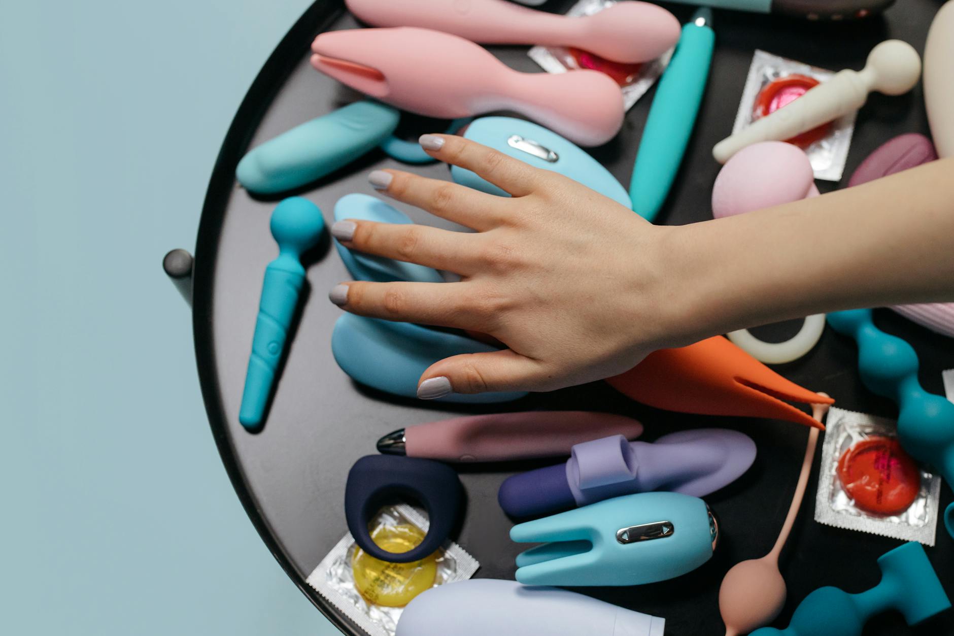 Intimate close-up of hands holding a sleek blue vibrator against a purple background
