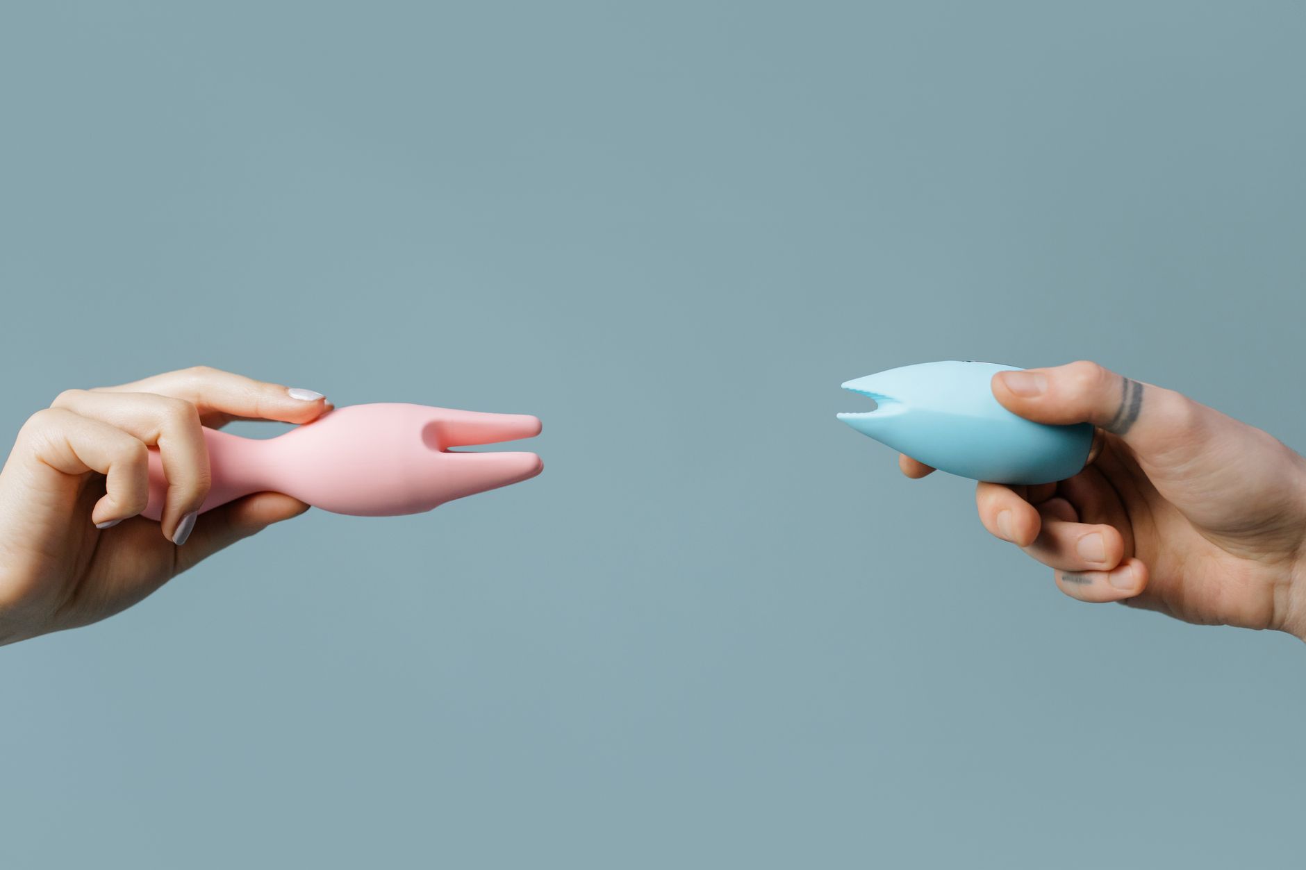 A hand holding an orange vibrator against a minimalistic purple backdrop, showcasing modern sensuality