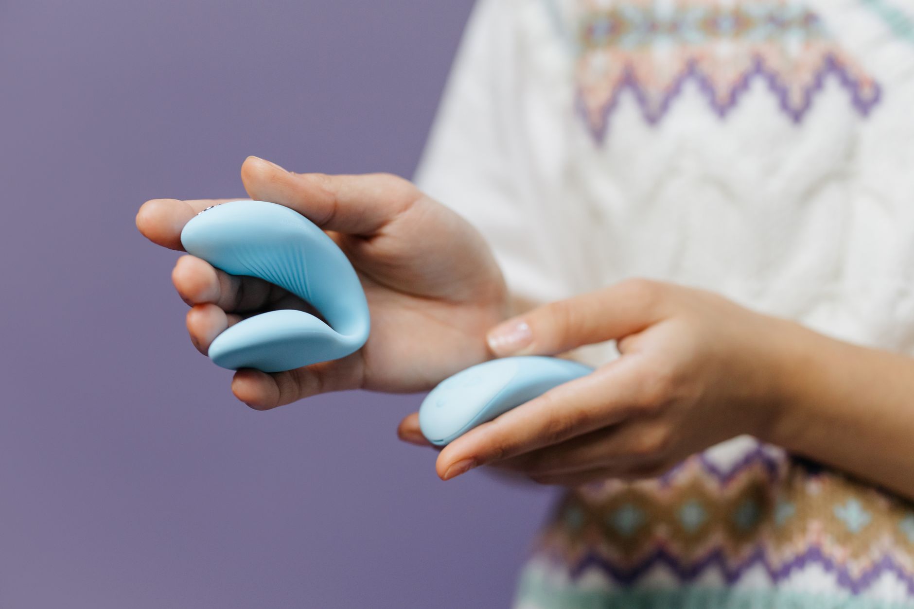 Hand holding a sleek blue lemon clitoral vibrator against a purple background, representing solo pleasure and freedom from performance pressure.
