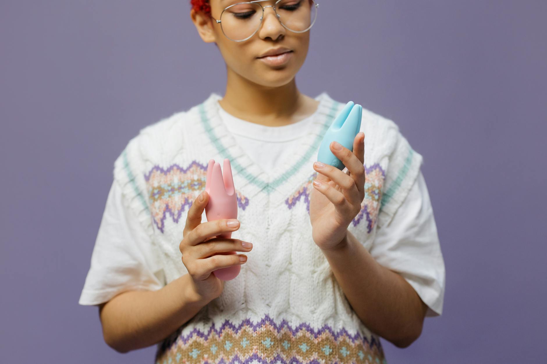 Woman holding blue and pink clitoral vibrators, representing tools for sensation recovery.