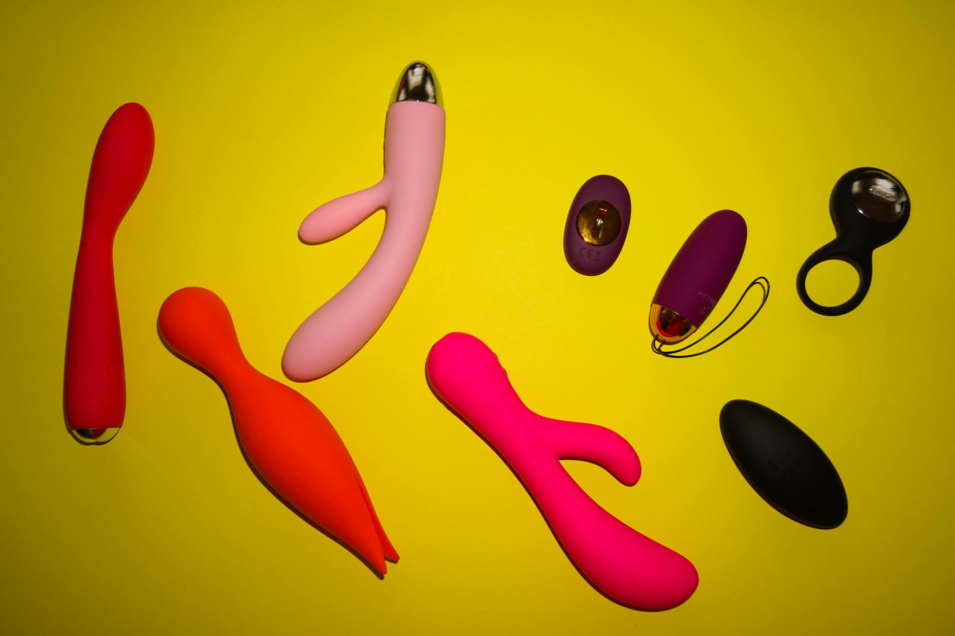 Vibrant collection of various clitoral vibrators arranged on a bright yellow surface